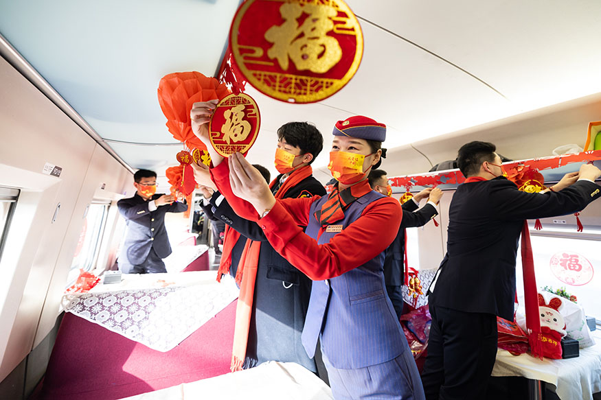 西安北至深圳北G824次列車,高鐵和地鐵乘務員一起貼窗花、掛福聯打造迎新年聯歡車廂。劉翔 攝