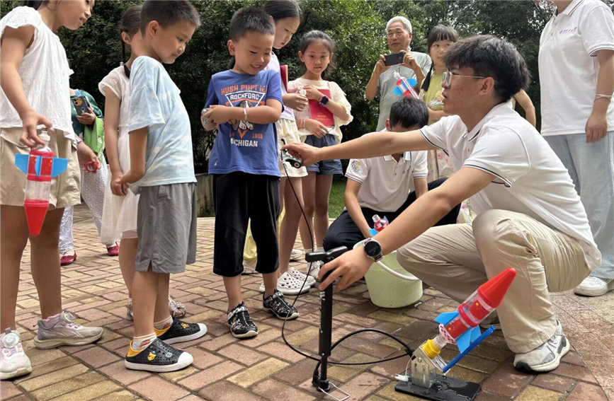 7月8日，高校志愿者在西安市雁塔區(qū)杜城街道金地西灃公元社區(qū)指導孩子們制作水火箭。杜城街道辦供圖