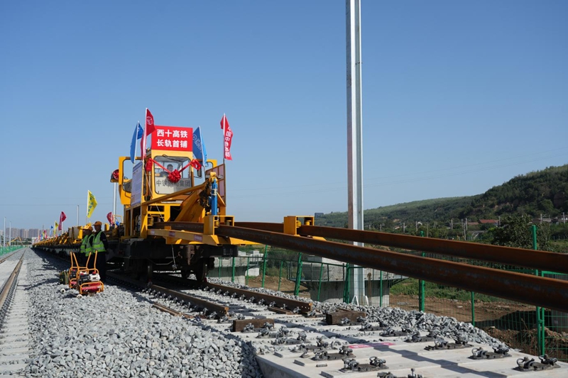在西十高鐵施工現(xiàn)場(chǎng)，鋪軌機(jī)正在將首對(duì)500米長(zhǎng)鋼軌平穩(wěn)地鋪設(shè)在無(wú)砟軌道板。籍振新攝