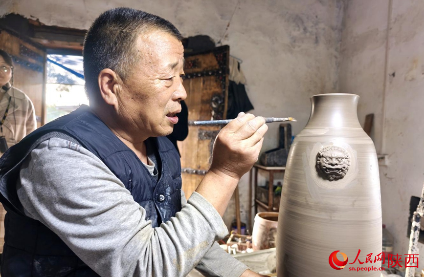 國家級非物質(zhì)文化遺產(chǎn)澄城堯頭陶瓷燒制技藝代表性傳承人劉忠陽對坯體進(jìn)行裝飾。人民網(wǎng) 王麗攝